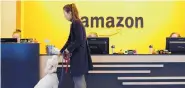  ?? ELAINE THOMPSON/ASSOCIATED PRESS ?? An Amazon employee gives her dog a biscuit as they head into a company building in Seattle.