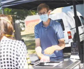  ?? Tyler Sizemore / Hearst Connecticu­t Media ?? A customer purchases Bees Knees ice pops at the Old Greenwich Farmers Market on June 24.