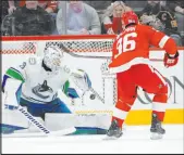  ?? Paul Sancya The Associated Press ?? Red Wings defenseman Jake Wallman scores against Canucks goalie Casey Desmith on an overtime penalty shot Saturday to cap Detroit’s 4-3 victory.