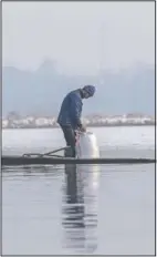  ??  ?? Wildlife worker Mohd Ashraf opens a bag of paddy to spread on the frozen surface of a wetland.