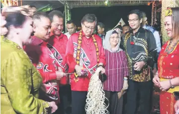  ??  ?? Abang Johari cuts the ribbon before entering a stall manned by Forum at the carnival. On his left is Juma’ani, while at respective second right and second left are Dennis and Antonio.