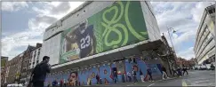  ?? KENNETH MAGUIRE — THE ASSOCIATED PRESS ?? A pedestrian crosses Dame Street below a giant Notre Dame football placard in Dublin, Ireland. Notre Dame will play Navy at Aviva Stadium on Saturday.