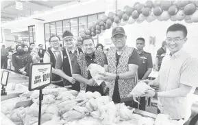  ?? — Gambar Roystein Emmor ?? MATAU REGA BARANG: Azman (dua kanan) megai siku manuk lebuh ti matau rega barang ari baruh SHMMP ba Farley Jalai Penrisse, kemari.