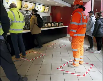  ?? FRANK AUGSTEIN — THE ASSOCIATED PRESS ?? People stand in marked places to keep a social distance at a fast food restaurant in London March 20.