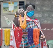  ??  ?? A Maasai woman sets up her stand displaying hand-made crafts.