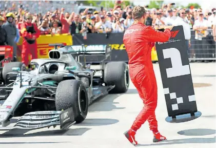  ?? AFP ?? Vení para acá. Sebastian Vettel lleva el “1” al lugar donde no quiso dejar su Ferrari en señal de protesta.