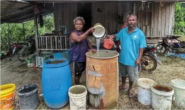  ?? — Bernama ?? It’s a hard life: Kampung denai orang asli Hanapi Titi (right) and awang Kelang showing rain water that they store for their everyday use in rompin, Pahang.