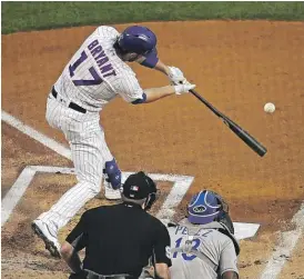  ?? JONATHAN DANIEL/GETTY IMAGES (ABOVE), KAMIL KRZACZYNSK/AP ?? Kris Bryant warms up before the game Monday (left), then hits a double (above) in the first inning against the Royals.