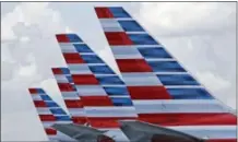  ?? THE ASSOCIATED PRESS ?? This photo shows the tails of four American Airlines passenger planes parked at Miami Internatio­nal Airport, in Miami. American said Tuesday it will offer free meals to everyone in economy on certain cross-country flights starting May 1.