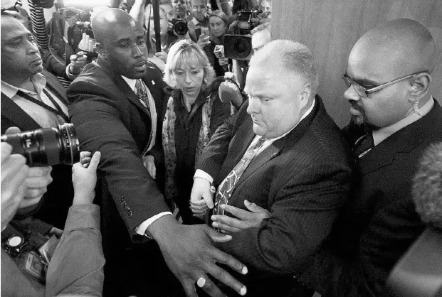  ?? TylerAnder­son/ National Post ?? Flanked by bodyguards, embattled Toronto Mayor Rob Ford, holding his wife Renata’s hand, leaves a press conference at city hall on Thursday.