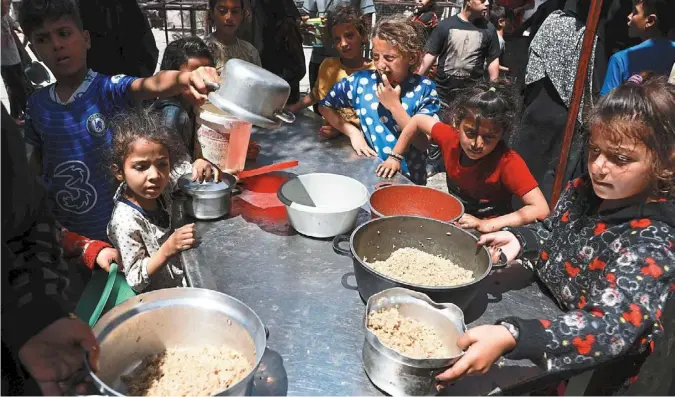  ?? ?? Long-awaited relief: Displaced Palestinia­n children lining up to receive food in Rafah on the southern Gaza Strip. —AFP