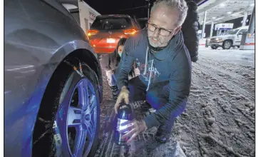  ?? Randall Benton The Associated Press ?? Rob Hager, of Redwood City, Calif., removes tire chains Tuesday at a gas station in Camino, Calif. He and his family spent more than five hours in traffic along U.S. 50. They were headed east to the Lake Tahoe area for skiing but gave up.