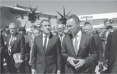  ?? MICHEL EULER, POOL / THE ASSOCIATED PRESS ?? French President Emmanuel Macron, left, visits the Paris Air Show Monday in Le Bourget, north of Paris, with the CEO of Airbus, Fabrice Brégier, right, after landing in an Airbus A400-M military transport, seen behind the two.