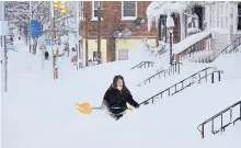  ?? GREG WOHLFORD/ERIE TIMES-NEWS ?? Rochelle Carlotti, 28, shovels steps near her home after a record snowfall on Tuesday in Erie, Pa. The National Weather Service office in Cleveland says Monday’s storm dumped 34 inches of snow.