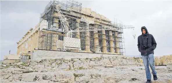  ?? FOTO: REUTERS ?? Un hombre camina ayer frente al templo en reparación del Parthenon, en la Acrópolis, en Atenas, Grecia.