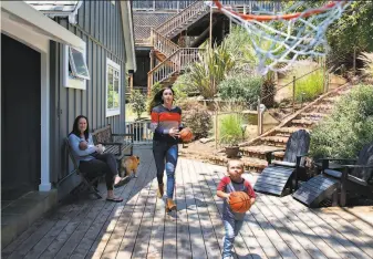  ?? Kate Munsch / Special to The Chronicle ?? Jennifer Azzi holds daughter Camden while her wife Blair Hardiek plays basketball with their 3yearold son Macklin, who is so excited to have a little sister “he can barely contain himself.”