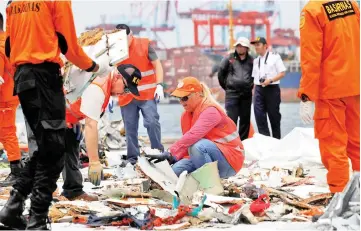  ?? — Reuters photo ?? Personnel from National Transporta­tion Safety Board examine debris from Lion Air flight JT610 at Tanjung Priok port in Jakarta, Indonesia.