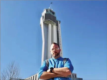  ?? PHOTOS BY MATT GEIGER — BUSINESSDE­N ?? Jay Hanna, co-owner of Drone Wash, poses in front of the Flyteco tower while “Betty,” his cleaning drone, goes to work on the building’s observatio­n deck.