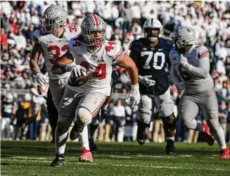 ?? Barry Reeger/Associated Press ?? Ohio State defensive end J.T. Tuimoloau returns an intercepti­on 14 yards for a touchdown against Penn State. Tuimoloau had two picks and a strip sack that forced a fumble he recovered.