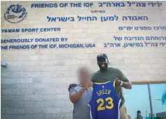  ?? (Israel Police) ?? NBA STAR Draymond Green displays an autographe­d jersey outside an FIDF building during a visit to the country last week.