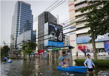  ?? — AFP photo ?? File photo shows a woman being ferried on a boat in the flooded section of Bangkok, when the year’s monsoon season brought the worst floods in decades with a fifth of the city under water.