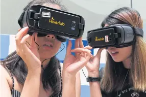  ??  ?? Students Tan Tong (left) and Chin Hui Shan watch virtual reality simulation­s of men making lewd comments, as part of the Girl, Talk project, aimed at helping women fight back against harassment in Singapore.