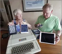  ?? ELAINE THOMPSON/ASSOCIATED PRESS ?? Kathy and Steve Dennis display several of their own cell phones and computer tablets along with their 1980’s-era Apple II Plus computer bought for their then young sons in Bellevue, Wash. Things have changed with their grandkids and their phones.