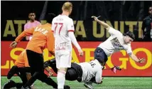  ?? CURTIS COMPTON / CCOMPTON@AJC.COM ?? Security guards tackle an Atlanta United fan who ran onto the pitch as New York Red Bulls midfielder Daniel Royer looks on during their MLS soccer match on Sunday in Atlanta.