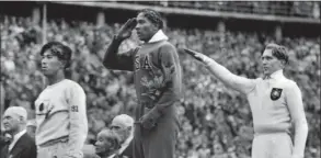  ?? Associated Press file photo ?? America’s Jesse Owens, center, salutes during the presentati­on of his gold medal for the long jump after defeating Germany’s Lutz Long, right, during the 1936 Summer Olympics in Berlin.