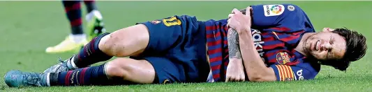  ?? — AP ?? Lionel Messi of Barcelona grimaces after a fall that broke a bone in his hand during the Spanish league match against Sevilla at Camp Nou in Barcelona on Saturday.