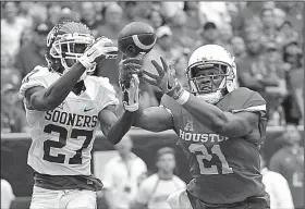  ?? AP/GEORGE BRIDGES ?? Houston wide receiver Chance Allen (21) and Oklahoma cornerback Dakota Austin reach for a pass during the second half of the No. 15 Cougars’ 33-23 victory over the No. 3 Sooners on Saturday at NRG Stadium in Houston.