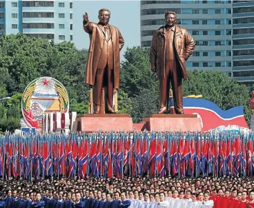  ?? /Reuters ?? Anniversar­y parade: People carry flags in front of statues of North Korean founder Kim Il-sung, left, and late leader Kim Jong-il during a military parade marking the 70th anniversar­y of North Korea’s foundation in Pyongyang on Sunday.