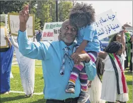  ??  ?? Sudanese American Soccer Federation tournament organizer Yasir Nasir holds his 3-year-old daughter, Ghazal, as he dances during the tournament’s welcoming ceremony at Afrim’s Sports Park in Colonie on Saturday.