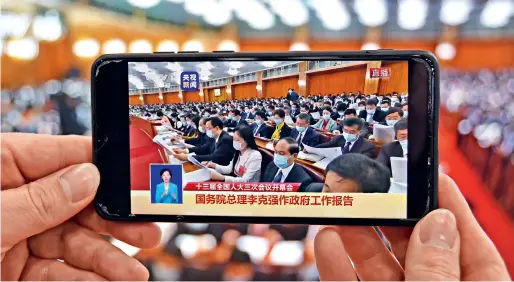 ??  ?? Le 22 mai 2020, les habitants du district de Fushan à Yantai (Shandong) suivent l’ouverture de la troisième session de la XIIIe APN sur leurs téléphones portables.