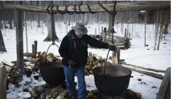  ??  ?? Jim Aikenhead demonstrat­es the iron kettles that were once used by early settlers to boil sap into maple syrup.