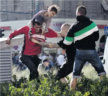  ?? MARKO DROBNJAKOV­IC/AP ?? A Syrian man carrying a child scuffles with a Hungarian nationalis­t at a train station in Budapest on Friday.