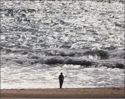  ?? Genaro Molina Los Angeles Times ?? A BEACHGOER walks on a nearly empty coastline Friday in Playa del Rey. Many public places in L.A. County are closed to slow the coronaviru­s spread.