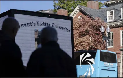  ?? SOPHIE PARK — THE NEW YORK TIMES ?? People stop to look at a doxing truck rented by Accuracy in Media, a conservati­ve activist group, displaying the names and faces of Harvard University students who were linked to an anti-israel letter, last week in Harvard Square in Cambridge, Mass.