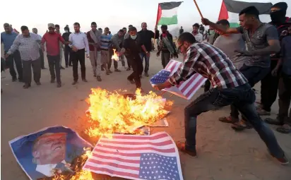  ?? (Ibraheem Abu Mustafa/Reuters) ?? PALESTINIA­NS BURN American flags and a poster of President Donald Trump yesterday at the border in the southern Gaza Strip.