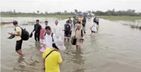  ?? — AFP ?? JANAKPUR: Passengers walk through the flooded Janakpur airport yesterday.