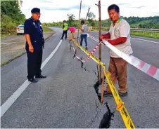  ??  ?? Workers put up barricade tapes along the road while Dennis (left) looks on.