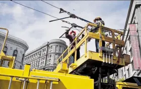  ?? Yue Wu / The Chronicle ?? Workers repair cables felled in an incident involving a Muni 5-Fulton bus that hurt three pedestrian­s at Market and Fifth streets during evening rush hour.