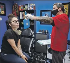  ?? GARY CORONADO Los Angeles Times ?? GENESIS NIEVES prepares to have her nose pierced at a Yuba City, Calif., shop in May. The region’s health officer said COVID-19 is now “roaring back” there.