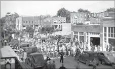  ?? Photo courtesy of the Siloam Springs Museum ?? A picture from the early 1930s shows a parade, complete with Ferris wheel, making its way down North Mt. Olive Street. The picture was taken from the second story of what is now Fire Station 2. The corner of the Herald-Leader office can be seen on the...