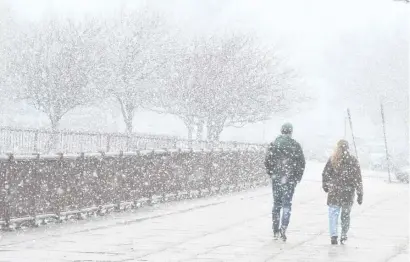  ?? JIM MICHAuD pHOTOS / BOSTOn HErAlD ?? A WINTER WONDERLAND: Weather in March can change quickly, from the 60s of Friday to snow showers and a strong wind making it feel like mid-winter Sunday, as people out walking found out Sunday on Day Boulevard in South Boston.