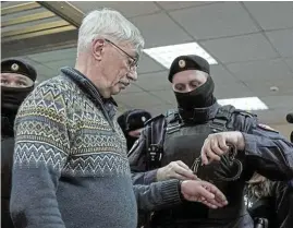 ?? /Reuters ?? Speaking out: A police officer puts handcuffs on Russian veteran human rights campaigner Oleg Orlov during a court hearing in Moscow, Russia, on Tuesday. Orlov was sentenced to two-and-a-half years in prison after he was found guilty of discrediti­ng Russia's armed forces.