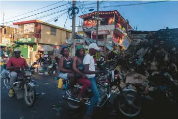  ?? ADRIANA ZEHBRAUSKA­S/THE NEW YORK TIMES ?? Motorbike traffic passes a large pile of trash Nov. 6 in the Petionvill­e area of Haiti’s capital, Port-au-Prince. Haiti is enduring a humanitari­an crisis in which basic services have ceased to function reliably.