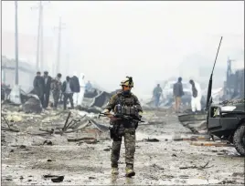  ?? Rahmatgul ?? The Associated Press An Afghan security force member walks around the site of a suicide bomb attack in Kabul, Afghanista­n, on Thursday. Taliban insurgents staged a coordinate­d attack targeting a security firm in the Afghan capital on Wednesday.