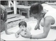  ?? (c) Paul Faris. Courtesy of Mary Ann Faris Thurmond and Tim Faris ?? Soldier James Nawa feeds his baby daughter Eileen at the internment camp at Rohwer in 1945. Many men left Rohwer to serve in World War II.