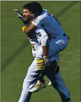  ??  ?? The A’s Tony Kemp jumps on Mitch Moreland after his batted ball was mishandled, scoring the decisive run.